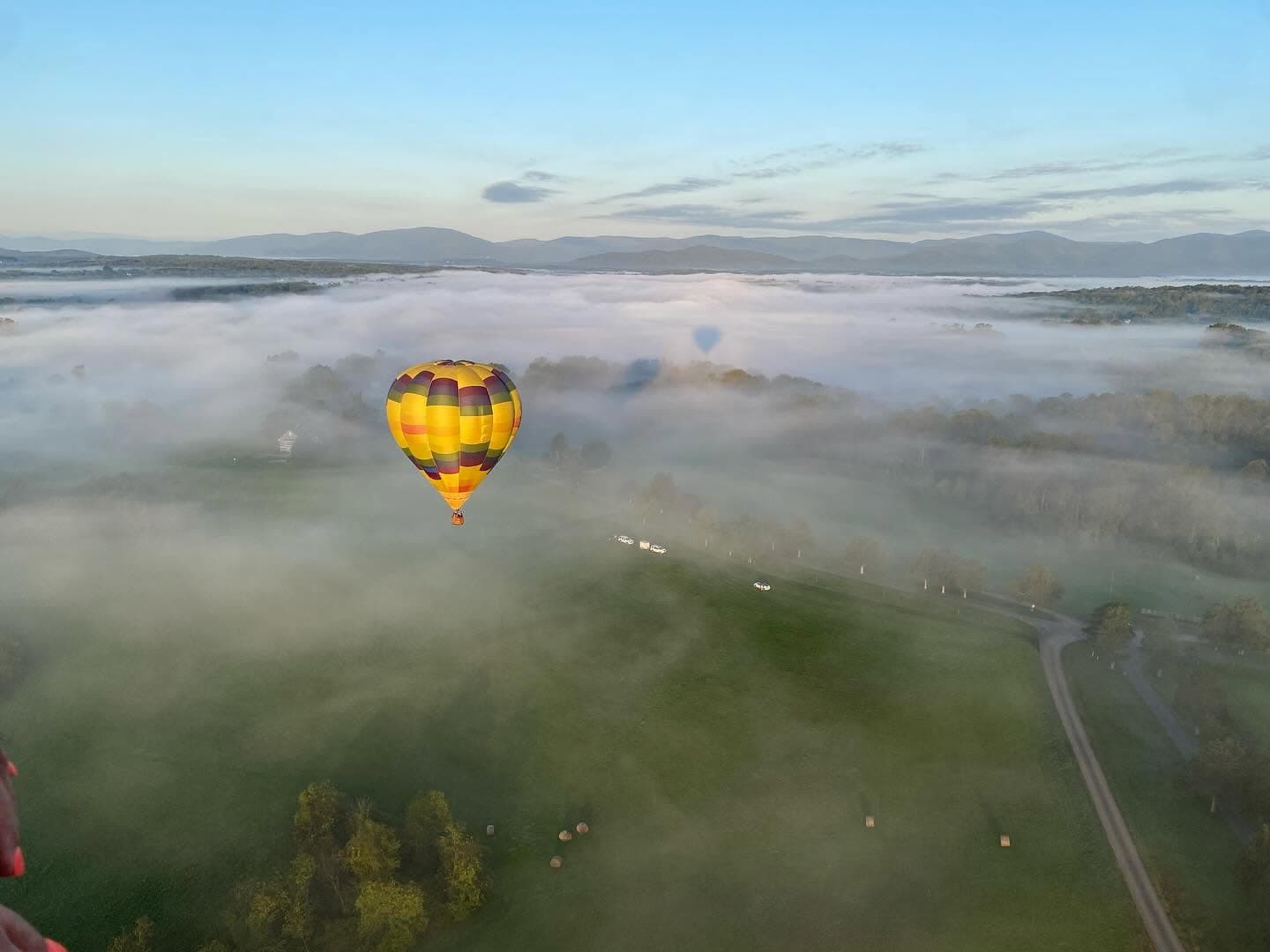 Hot air balloon floating through morning fog over Virginia fields