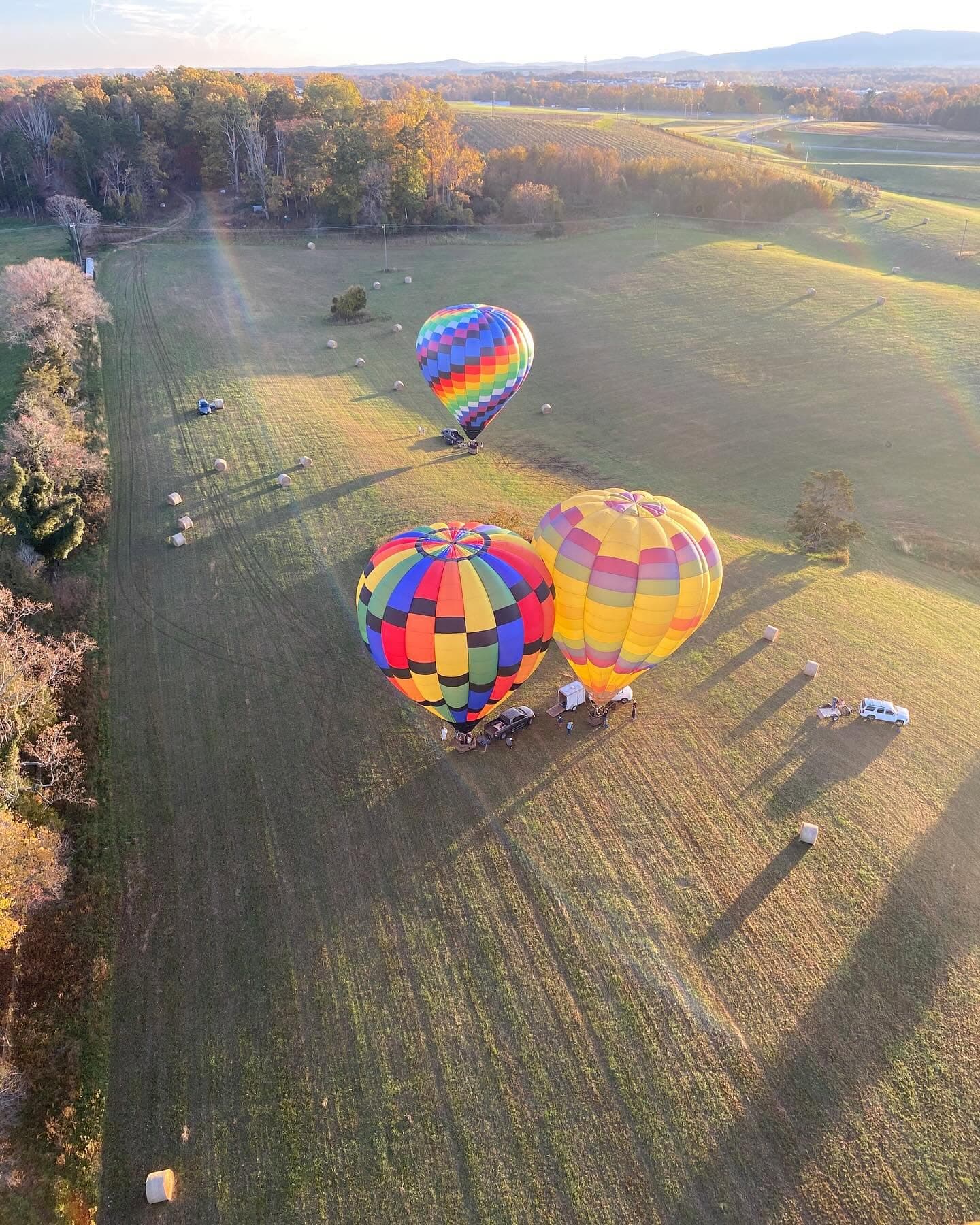Three hot air balloons launching from a Virginia field at golden hour