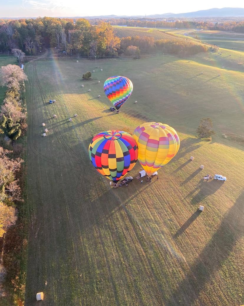 Three hot air balloons launching from a Virginia field at golden hour